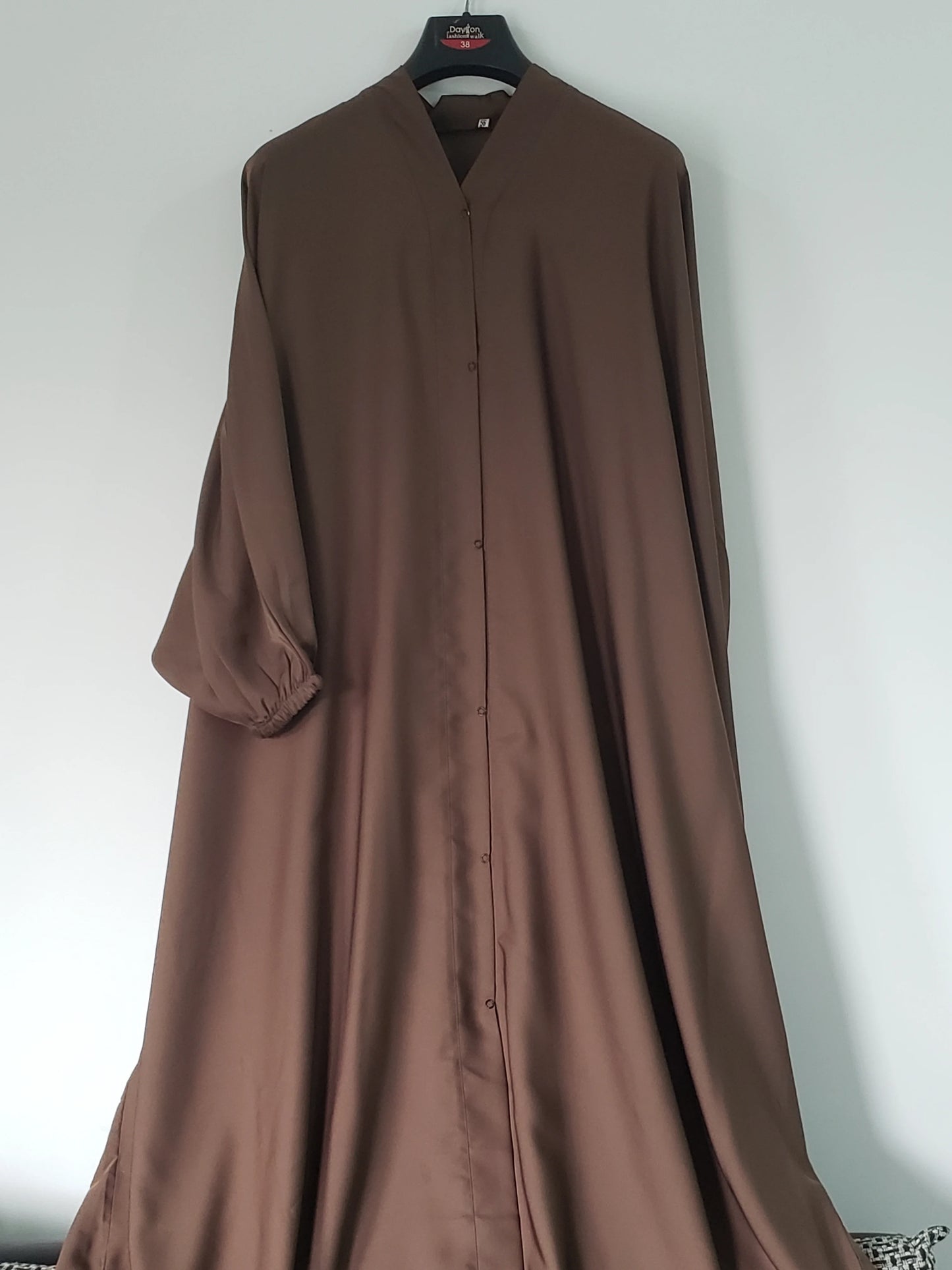 Brown long-sleeve dress on a hanger against a white wall